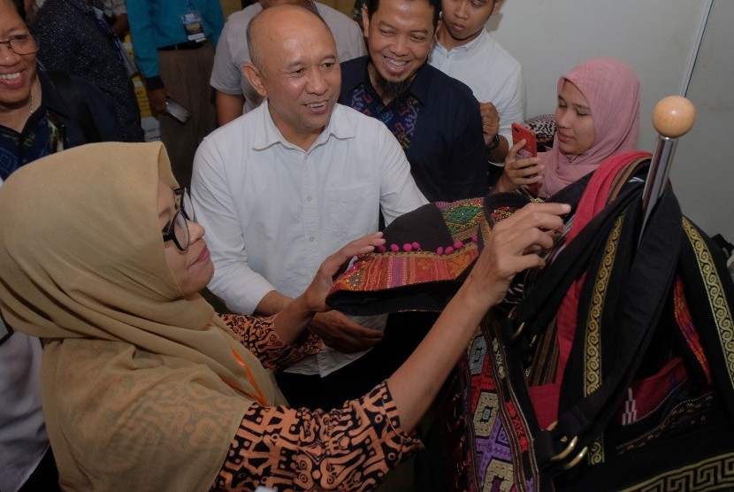 Menteri Koperasi dan Usaha Kecil Menengah (UKM) Teten Masduki (kedua kiri) melihat produk tas karya perajin UMKM disela Forum Bisnis Muhammadiyah Internasional 2019 di Denpasar, Bali, Senin (25/11/2019).