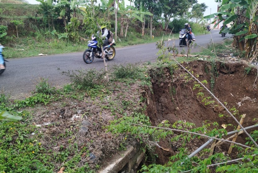 Warga melintas di Jalan Cisinga tepatnya di kilometer 4, Desa Karangsembung, Kecamatan Jamanis, Kabupaten Tasikmalaya, yang amblas akibat hujan besar, Selasa (26/11)