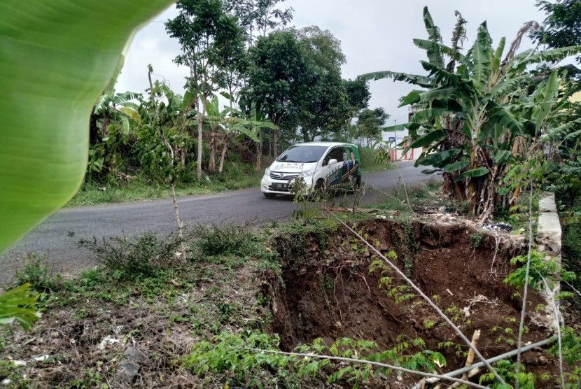 Warga melintas di Jalan Cisinga tepatnya di kilometer 4, Desa Karangsembung, Kecamatan Jamanis, Kabupaten Tasikmalaya, yang amblas akibat hujan besar, Selasa (26/11)