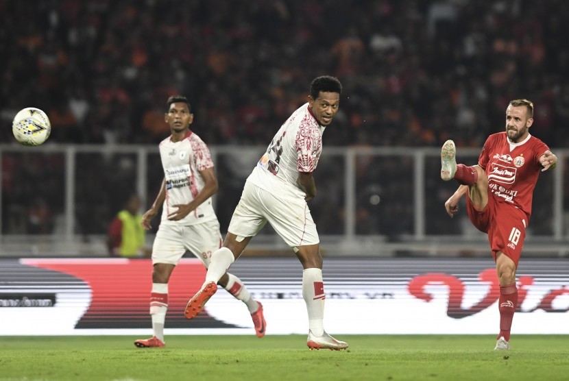 Gelandang Persija Jakarta Joan Tomas Campasol (kanan) dibayang-bayangi bek Persipura Jayapura Yohanis Tjoe (tengah) menendang bola yang menghasilkan gol pada laga lanjutan Liga 1 di Stadion Utama Gelora Bung Karno, Jakarta, Kamis (28/11/2019).