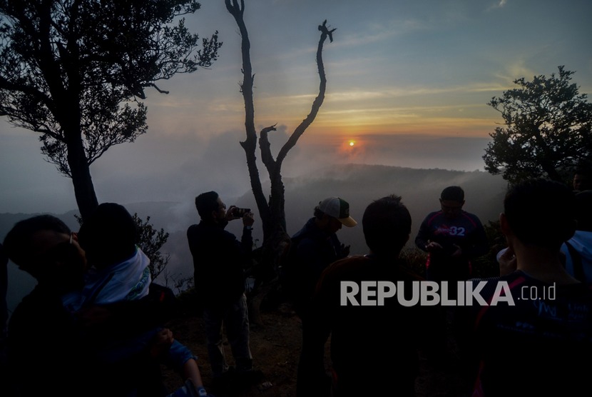 Wisatawan menikmati pemandangan matahari terbit dari Puncak Upas di Kabupaten Bandung Barat, Jawa Barat, Jumat (29/11/2019).