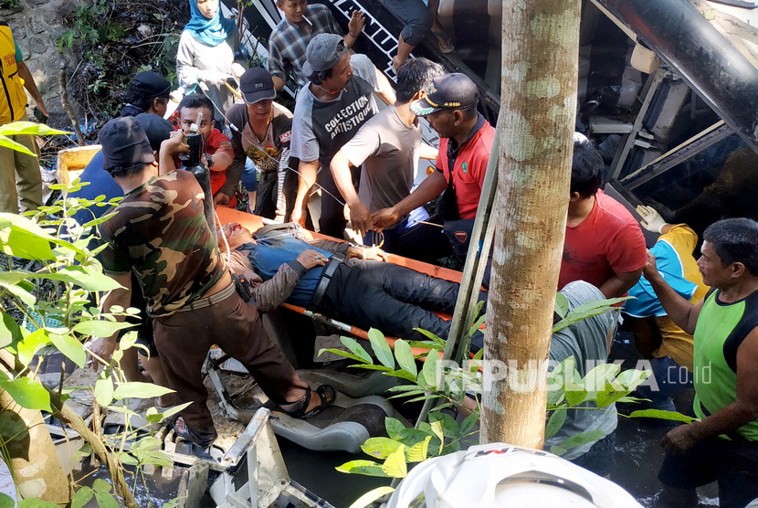 Warga dan petugas PMI mengevakuasi korban dari dalam Bus Pariwisata Fabian Anugerah Trans Nopol AG 7555 UR yang tertibat kecelakaan dan terjun ke Sungai Judel di jalan lintas Blitar-Malang di jalan raya Kesamben, Blitar, Jawa Timur, Sabtu (7/12/2019).