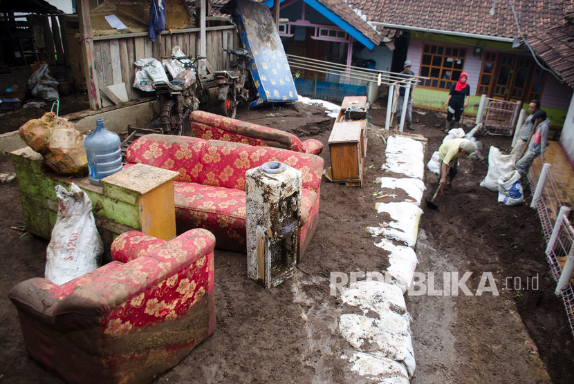 Warga membersihkan perabotan rumah tangga yang terkena lumpur pascabanjir bandang di Kertasari, Kabupaten Bandung.
