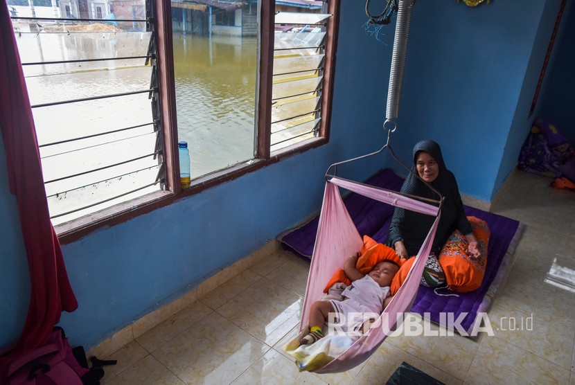 Seorang nenek menidurkan cucunya saat mengungsi di mushala di Desa Sahilan Darussalam akibat rumahnya banjir luapan Sungai Subayang di Kecamatan Gunung Sahilan Kabupaten Kampar, Riau, Rabu (11/12/2019). 