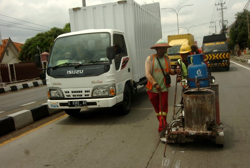 Pekerja melakukan pengecatan marka jalan di jalur Pantura Tegal, Jawa Tengah, Kamis (12/12/2019). 