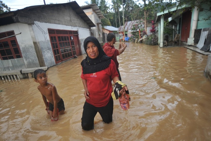 Warga melintasi banjir yang merendam pemukiman di Kampung Tarandam, Nagari Pasar Muara Labuah, Kab.Solok Selatan, Sumatera Barat, Jumat (13/12/2019).
