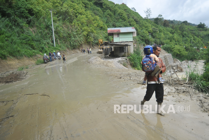 Ilustrasi. Pengendara meninggalkan motornya melewati jalan yang longsor di Nagari Lolo, Kecamatan Pantai Cermin, Kabupaten Solok, Sumatera Barat, Jumat (13/12/2019).