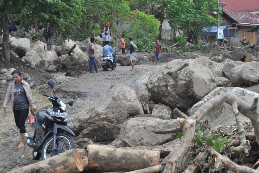 Warga berada disekitar tumpukan material yang terbawa banjir bandang dan menerjang pemukiman warga di Dusun Pangana, Desa Bolapapu, Kecamatan Kulawi, Kabupaten Sigi, Sulawesi Tengah, Jumat (13/12/2019).