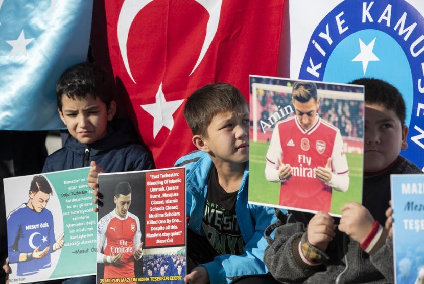 Para pemrotes Turki dan Uyghur memegang foto-foto pemain sepak bola Turki yang membela Arsenal Mesut Oezil karena pesan dukungannya kepada Turkestan Timur dan Uighur selama protes melawan Pemerintah China di Istanbul, Turki, 14 Desember 2019.