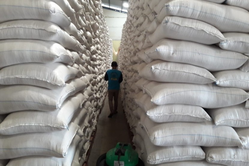Pemerintah Kota Sukabumi menyalurkan bantuan beras cadangan pangan pemerintah kepada warga yang terdampak bencana akhir-akhir ini.  Foto: Seorang pekerja melewati lorong yang dipenuhi tumpukan beras di gudang. 