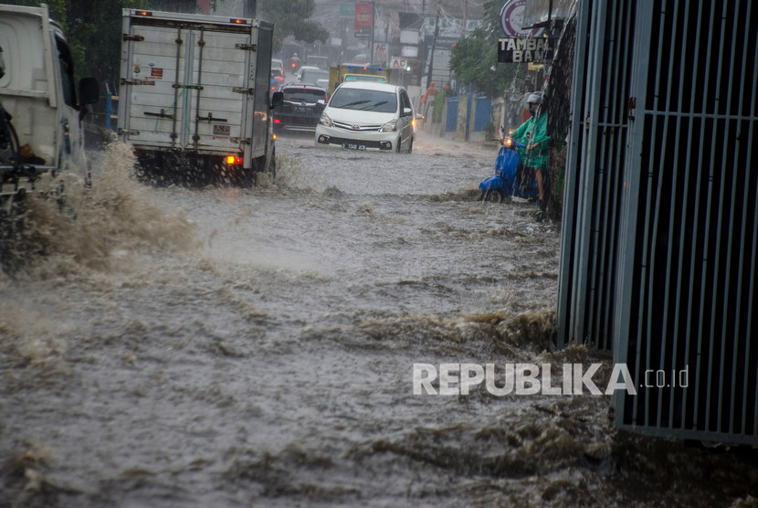 Pengendara melintasi derasnya arus air saat banjir di kawasan Cikutra, Bandung, Jawa Barat, Jumat (27/12/2019).
