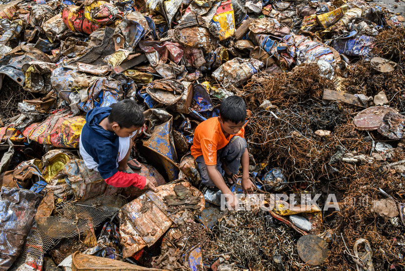 Anak-anak mencari sisa besi bekas di tumpukan limbah Bahan Beracun dan Berbahaya (B3) di Jakarta, Jumat (27/12/2019). 