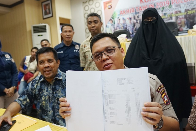 Kabid Humas Polda Gorontalo AKBP Wahyu Tri Cahyono (kanan) bersama penyidik menunjukKan barang bukti pada rilis pengungkapan kasus penipuan dan penggelapan penyelenggaraan perjalanan umrah di Mapolda Gorontalo, Kabupaten Gorontalo, Gorontalo, Jumat (27/12/2019).