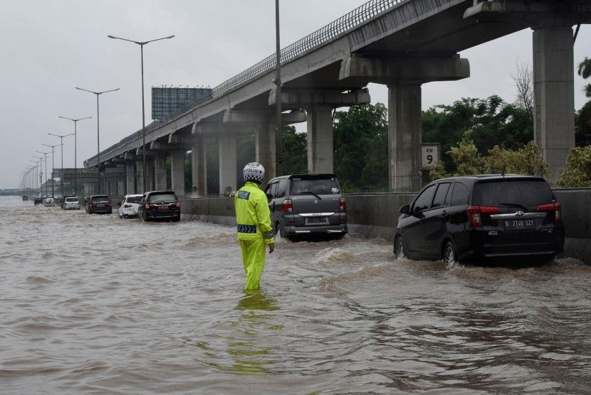 Petugas mengatur kendaraan yang melintasi genangan air ketika banjir merendam jalan Tol Cikampek di sekitar Jati Bening, Bekasi, Rabu (01/01/2020).