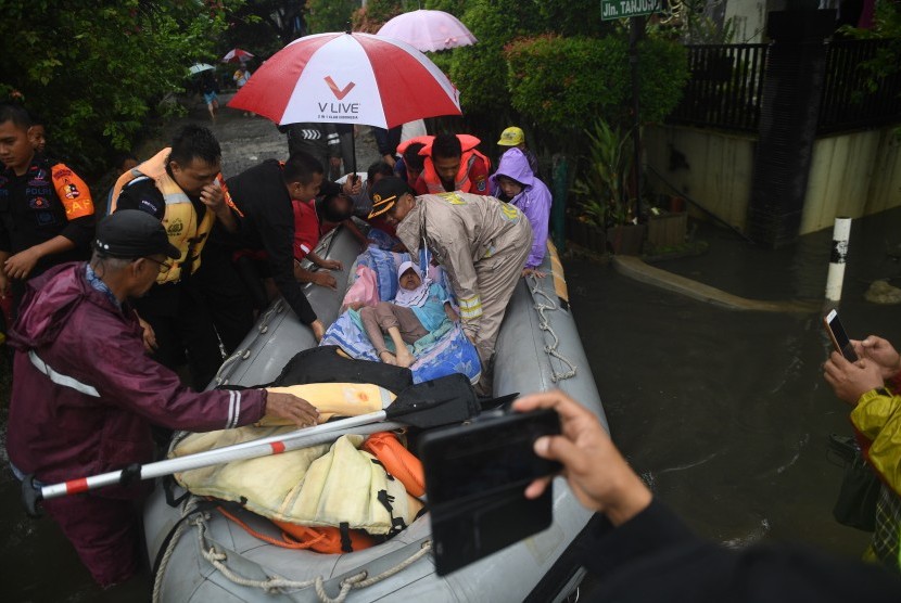 Petugas mengevakuasi warga yang sakit menggunakan perahu karet saat terjadi banjir di Perumahan Bukit Cengkeh 2, Depok, Jawa Barat, Rabu (1/1/2020). 
