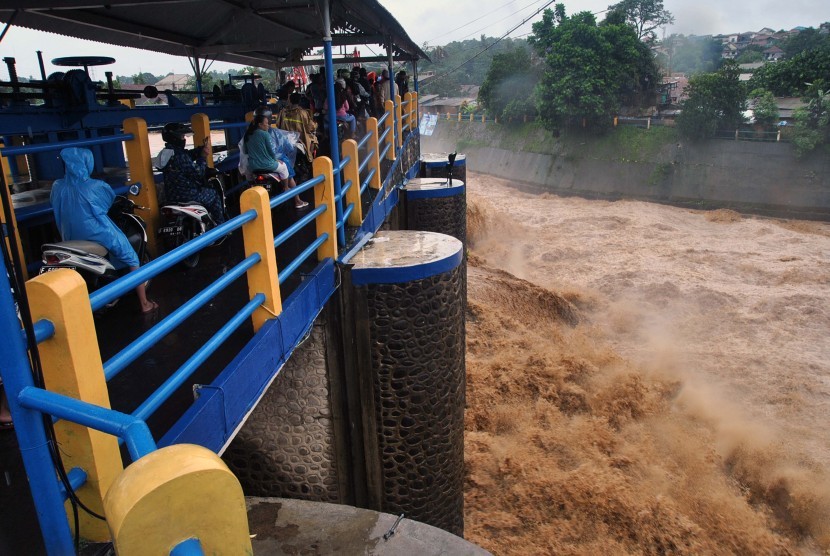 Sejumlah pengendara motor melintas diatas jembatan saat tinggi muka air sungai Ciliwung naik di Bendung Katulampa, Kota Bogor, Jawa Barat, Rabu (1/1/2020).