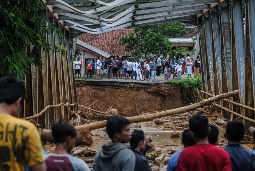 Sejumlah warga melihat kondisi jembatan yang rusak diterjang banjir bandang di Desa Sajira, Lebak, Banten, Rabu (1/1/2020). Warga Lebak Gedong, Kabupaten Lebak terisolasi karena jembatan putus akibat banjir.