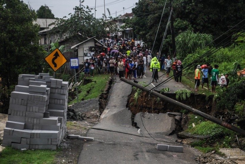 Sejumlah warga melihat kondisi jalan yang longsor akibat terkena terdampak banjir bandang di Desa Lebak Gedong Lebak, Banten, Rabu (1/1/2020).