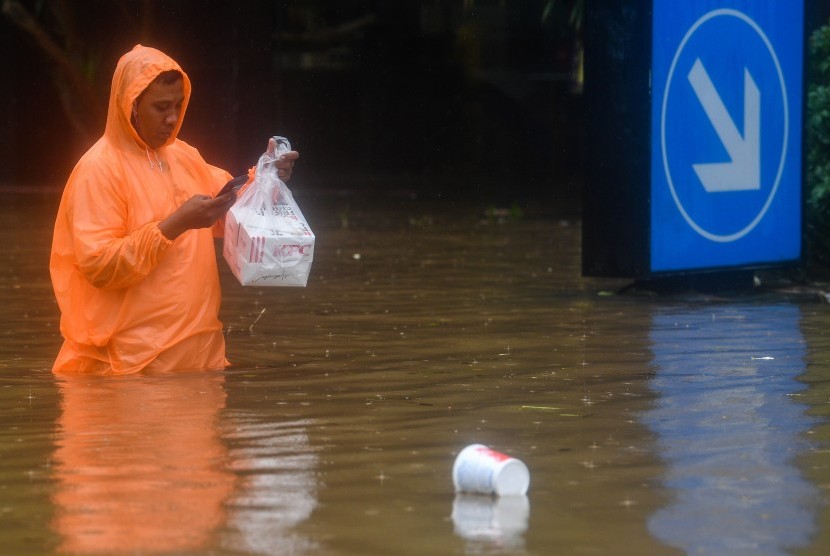 Kurir pengantar makanan melintasi Jalan Kemang Raya yang terendam banjir Jakarta Selatan, Rabu (1/1/2020).