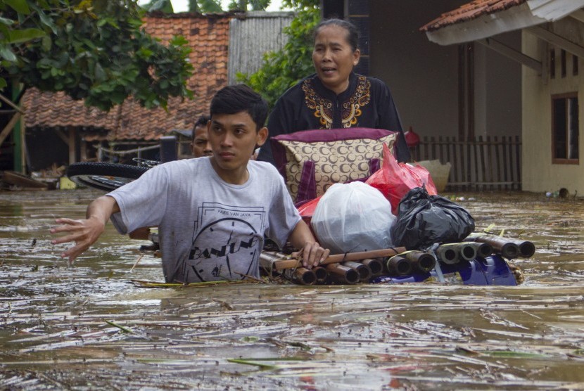 Warga mengevakuasi keluarganya mengunakan perahu rakit saat banjir di Desa karangligar, Karawang, Jawa Barat, Rabu (1/1/2020).