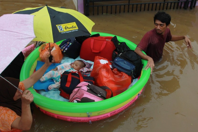 Warga dengan menggunakan perahu karet seadanya menyelamatkan bayinya dari dalam rumahnya yang terendam banjir di Perumaha Puri Bintaro Indah, Ciputat, Tangerang Selatan, Banten, Rabu (1/1/2020).