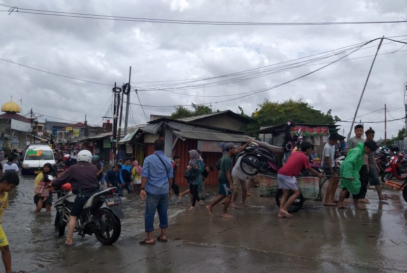 Sejumlah penyedia jasa ojek gerobak mengangkut motor maupun orang melewati genangan di Jalan Desa Semanan, Kelurahan Semanan Kecamatan Kalideres, Jakarta Barat, Kamis (2/1). 