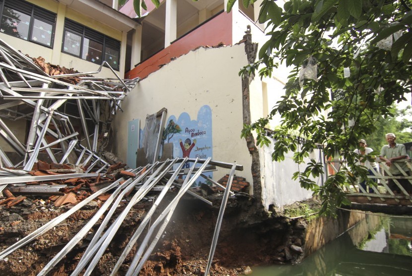 Dua orang warga melihat kondisi perpustakaan yang ambruk di SDN Beji 4, Kota Depok, Jawa Barat, Kamis (2/1/2020).