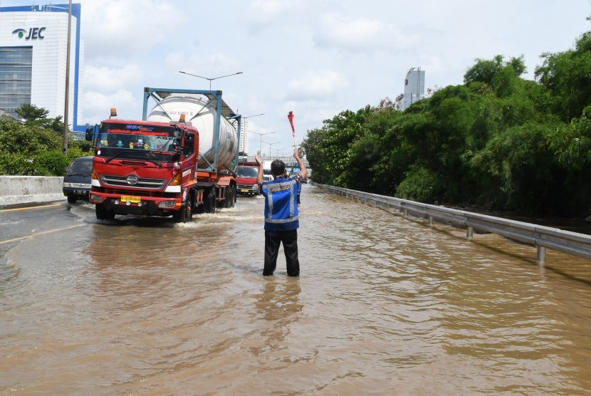 Petugas mengatur laju kendaraan yang melintasi banjir di jalan tol lingkar dalam Kebon Jeruk, Jakarta Barat, Kamis (2/1/2020). 