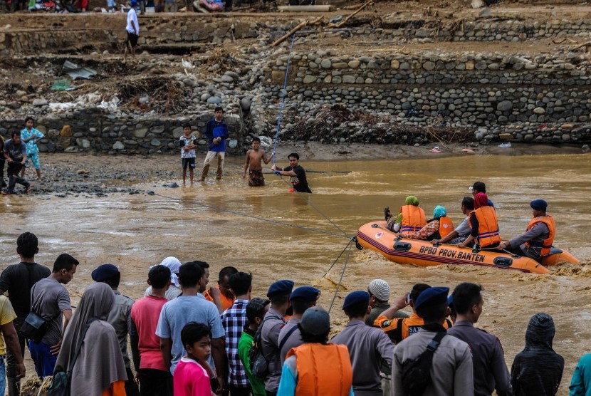 Sejumlah relawan membantu warga menyeberangi Sungai Ciberang untuk dievakuasi ke tempat aman di Kampung Susukan, Lebak, Banten, Kamis (2/1/2020). Sebanyak 28 jembatan di Kab Lebak rusak diterjang banjir bandang. 