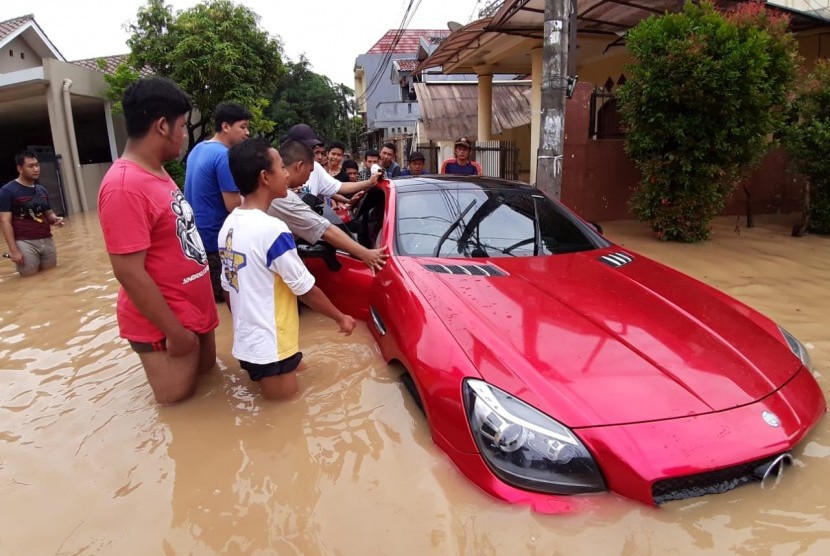 Sejumlah warga berusaha mendorong sedan mewah yang terjebak akibat banjir di Perumahan Vila Nusa Indah 1 RW 16, Kabupaten Bogor. Pemotret : Republika/Gunadi Supratman