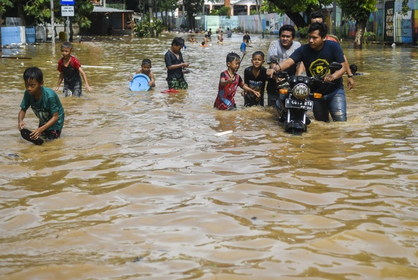 Warga melintasi banjir di kawasan Bukit Duri, Jakarta, Kamis (2/1/2020).