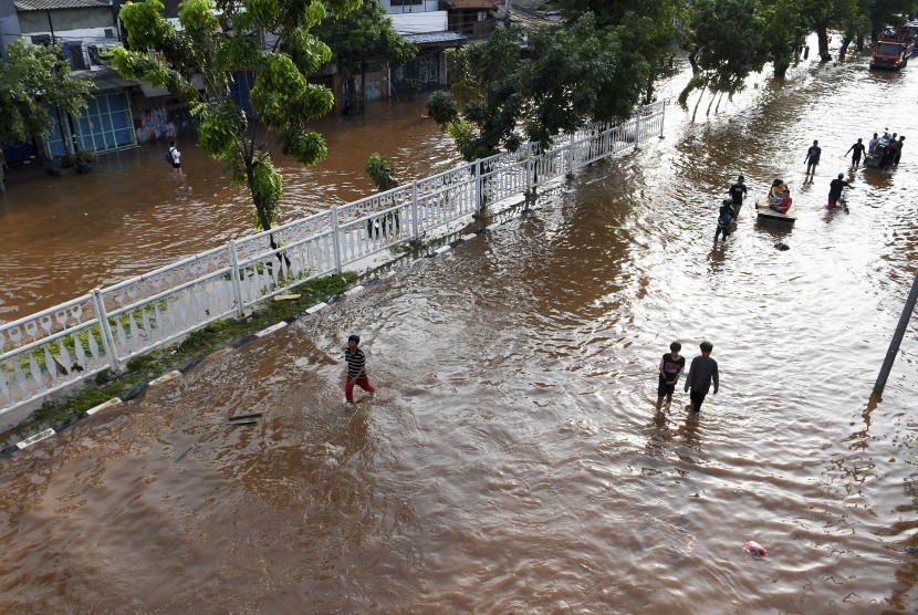 Warga melintasi banjir di Jalan Pangeran Tubagus Angke, Jelambar, Jakarta, Kamis (2/1/2020).