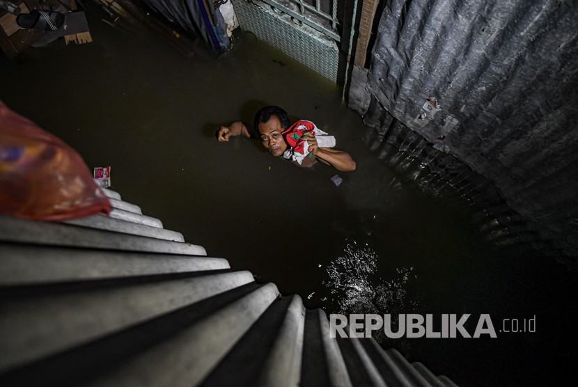 Seorang warga melintasi banjir di kawasan Kampung Baru, Kembangan, Jakarta Barat, Kamis (2/1/2020).