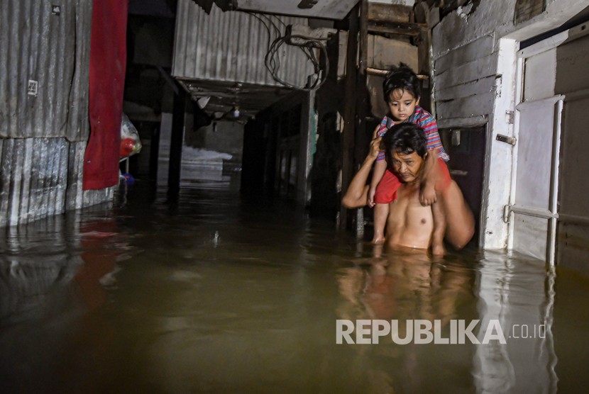Seorang warga menggendong anaknya melewati banjir di kawasan Kembangan, Jakarta Barat. ilustrasi