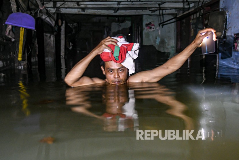 Seorang warga melintasi banjir di kawasan Kampung Baru, Kembangan, Jakarta Barat, Kamis (2/1/2020). 