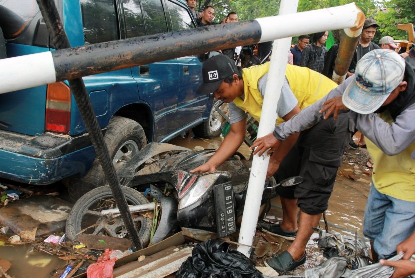 Petugas kebersihan dari Pemkot Tangerang mencoba menyingkirkan bangkai kendaraan yang terseret banjir di perumahan Ciledug Indah, Tangerang, Banten, Jumat (3/1/2020).