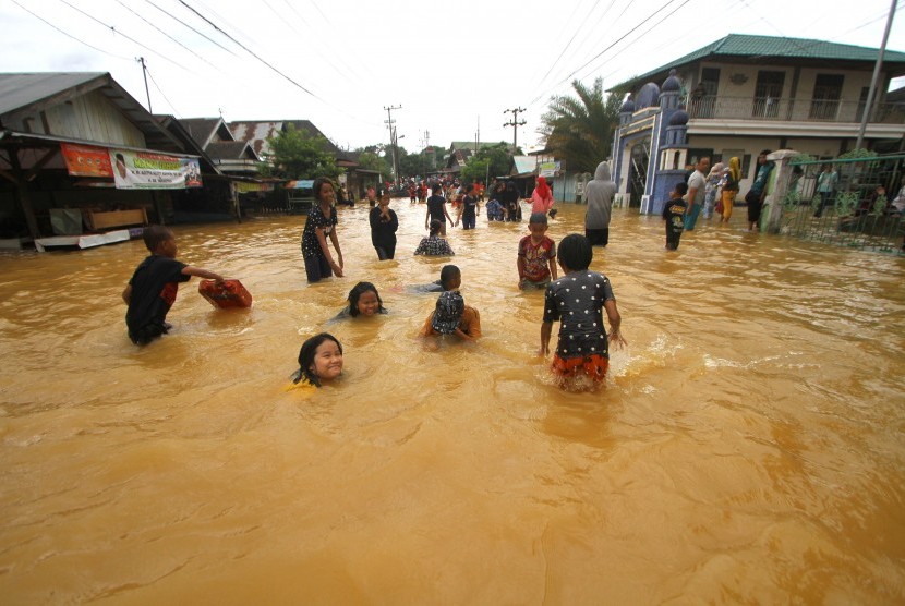 Anak-anak bermain air saat banjir di kawasan Cempaka, Banjarbaru, Kalimantan Selatan, Ahad (5/1/2020). Setidaknya, ada empat bahaya yang mengintai anak yang main dengan air banjir.