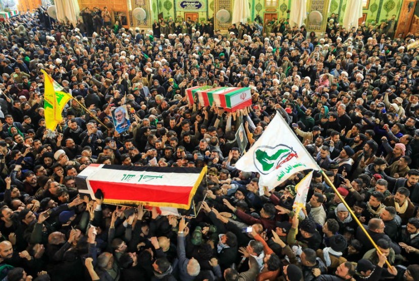 Orang-orang berduka di sebelah peti mati Abu Mahdi al-Muhandis dan Qassem Soleimani yang tewas selama prosesi pemakaman di Najaf, Irak, 4 Januari 2020.