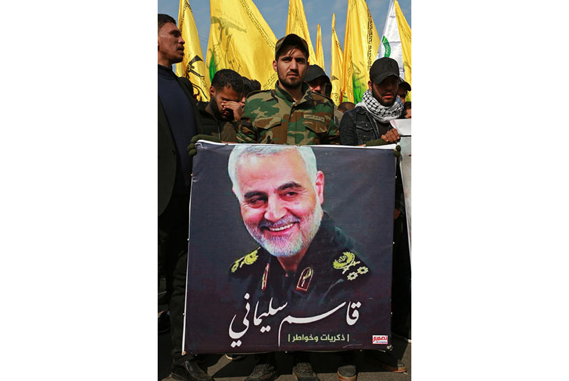 Seorang anggota kelompok bersenjata Syiah Irak yang didukung Iran pasukan mobilisasi populer membawa gambar Qassem Soleimani yang terbunuh di Baghdad tengah, Irak, 04 Januari 2020.