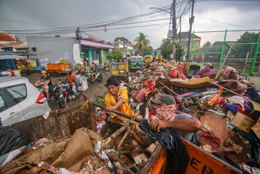 Petugas Dinas Lingkungan Hidup Kota Tangerang memindahkan sampah yang menumpuk di sisi jalan pascabanjir di Pondok Bahar, Kota Tangerang, Banten, Senin (6/1/2020).