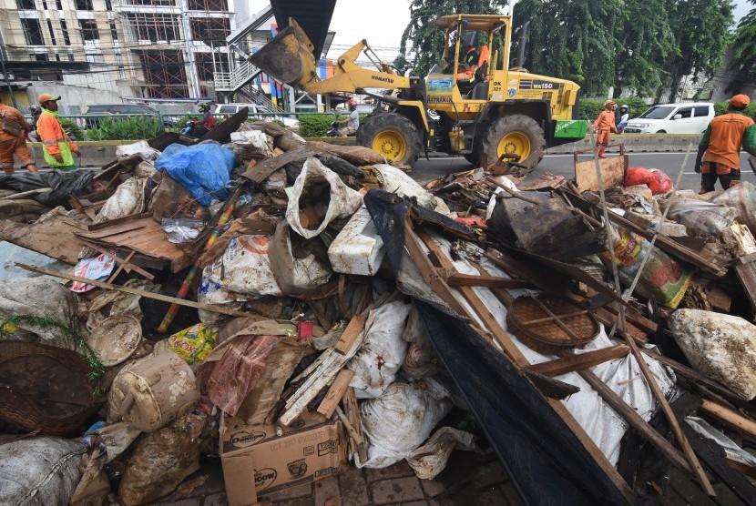 Petugas PPSU dibantu alat berat mengumpulkan sampah sisa banjir dari wilayah permukiman Bidara Cina di Jalan Otto Iskandar Dinata, Jakarta, Senin (6/1/2020).