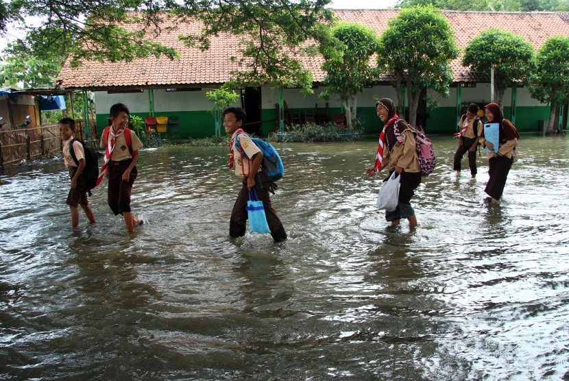 Sejumlah siswa melintas di area sekolah yang tergenang banjir di SDN Buni Bakti 04, Kabupaten Bekasi, Jawa Barat, Selasa (7/1/2020). 