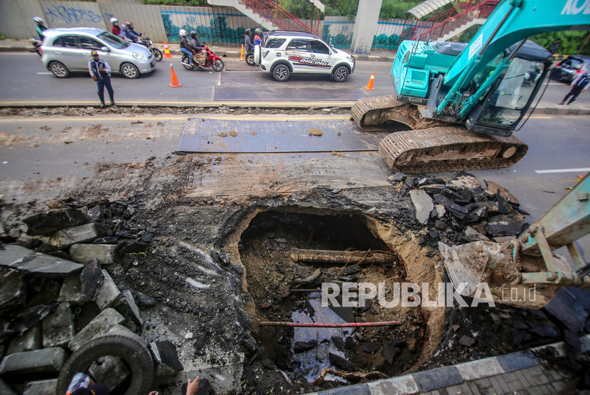 Petugas melakukan proses perbaikan jalan yang ambles di Jalan Daan Mogot, Kota Tangerang, Banten, Ahad (12/1).