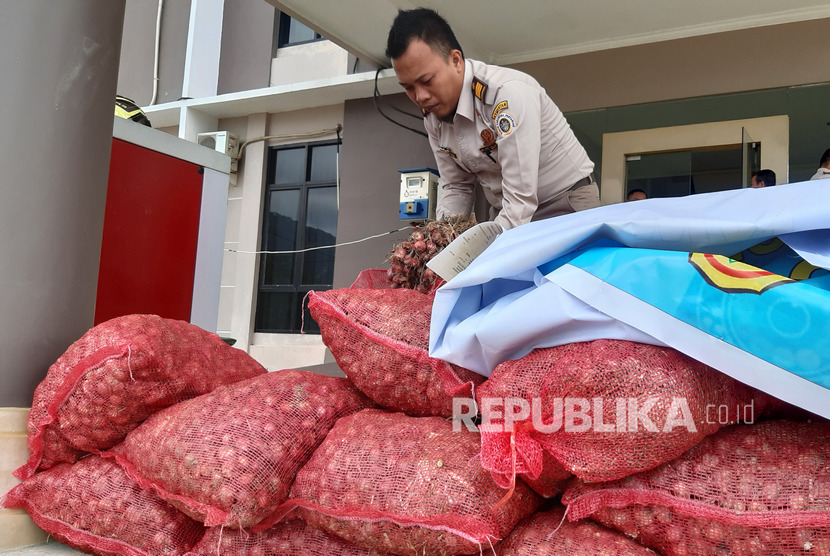 Seorang petugas memeriksa tumpukan karung berisi bawang merah illegal asal Malaysia saat rilis kasus di Stasiun Karantina Pertanian Kelas I Entikong, Kabupaten Sanggau, Kalimantan Barat, Rabu (15/1/2020).