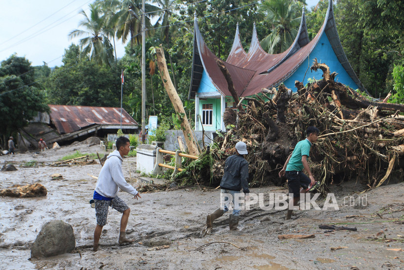 Warga melintas di depan rumah yang rusak diterjang banjir bandang, di Nagari Malalo, Tanah Datar, Sumatera Barat. Warga di Malalo masih khawatir akan terjadi banjir bandang. Ilustrasi.