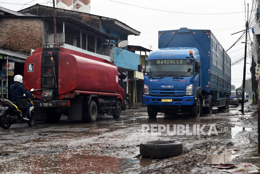 Pengendara memperlambat laju kendaraannya saat melintasi jalan rusak berlubang yang digenangi air dan lumpur di Jalan Pejuang, Pondok Ungu, Bekasi, Kamis (23/1/2020).