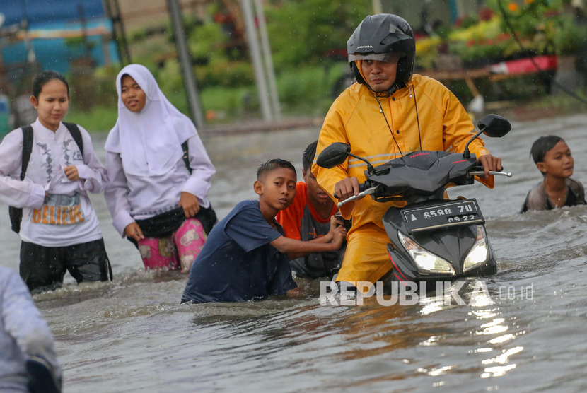 Warga melintasi banjir di Total Persada, Periuk, Kota Tangerang, Banten, Jumat (24/1/2020).