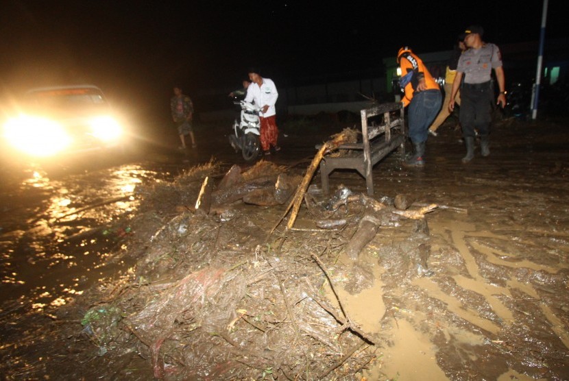 Warga membantu seorang pengendara motor melintas di jalan yang penuh lumpur saat terjadi banjir bandang di Petungsewu, Dau, Malang, Jawa Timur
