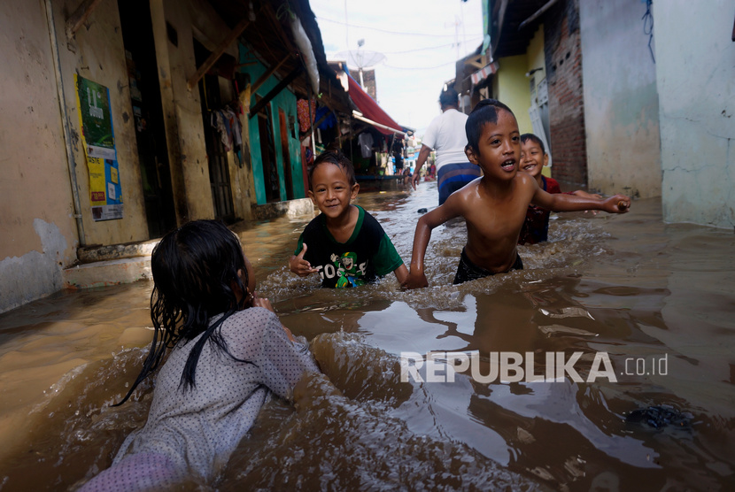 Sejumlah anak-anak bermain di genangan banjir di rumahnya di Kelurahan Sampangan Gang 5, Pekalongan, Jawa Tengah, Ahad (26/1/2020).