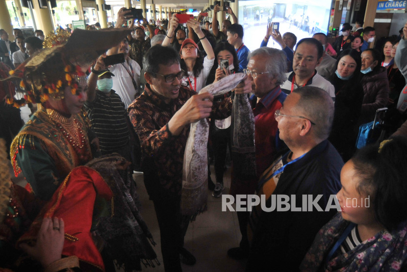 Gubernur Sumatera Barat Irwan Prayitno (kedua kiri) mengalungkan kain kepada salah satu wisatawan asal China saat penyambutan di Bandara Internasional Minangkabau (BIM), Padangpariaman, Sumatera Barat, Ahad (26/1/2020). 